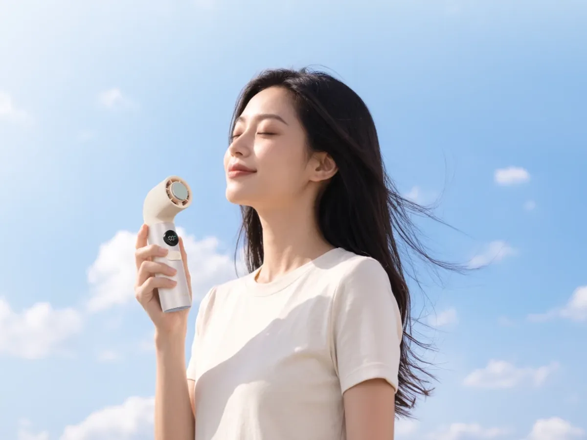 หญิงสาวถือพัดลม VIDAGO สี Light Gold ด้วยมือเดียว เป่าลมเข้าหาใบหน้า